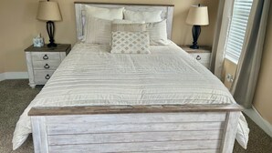 Una camera da letto con un letto con struttura in legno, un poggiatesta e due comodini con lampade.