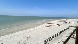 Une plage avec une promenade en béton, un rivage sablonneux et un ciel bleu dégagé.