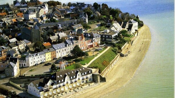 Une ville côtière dotée de bâtiments historiques, d’une plage et d’une structure fortifiée.