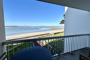 Enjoy the serene beach view from this balcony with a table and chair.