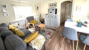 A cozy living room with a sofa, armchairs, a dining table, and a kitchen area.