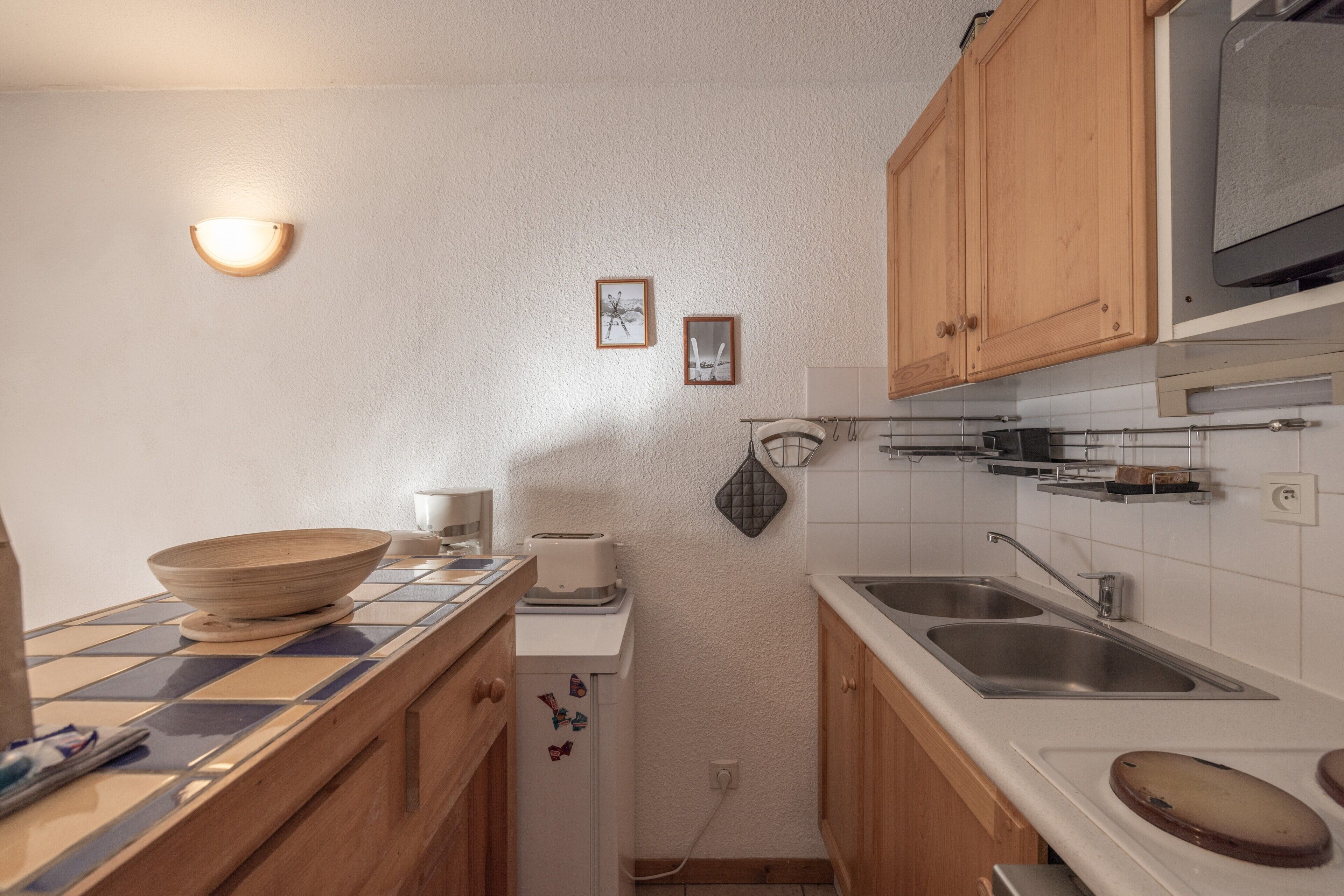 Una cocina compacta equipada con microondas, tostadora y dos fregaderos.