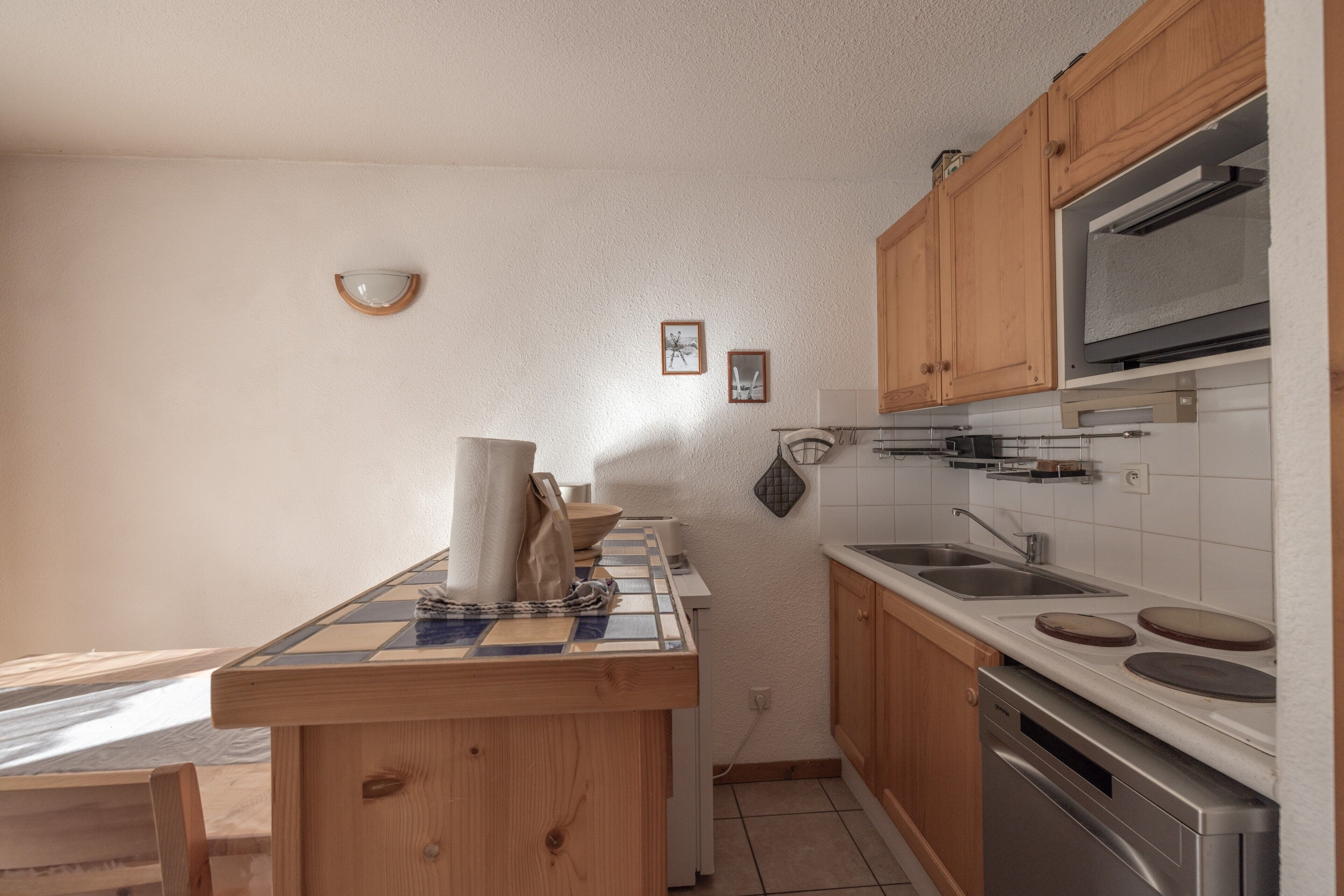 A kitchen with wooden cabinets, a microwave, a sink, and a tiled backsplash.