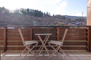 A balcony with a wooden railing, two white folding chairs, and a small table. - Apartment 'Residence Des Neiges - Immoclean' with Mountain View, Balcony and Wi-Fi (Morillon)