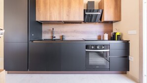 Une cuisine moderne équipée d’un four encastré, d’un four à micro-ondes et d’une machine à café posée sur le plan de travail.