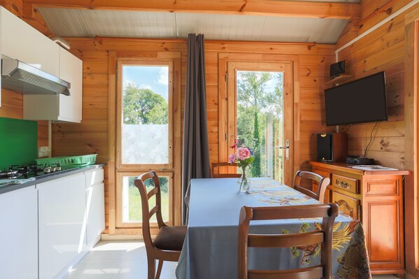 A wooden cabin with a kitchen, dining area, and a TV mounted on the wall.