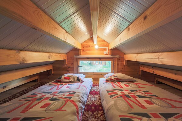 Une cabane avec deux lits, un plafond en bois et une fenêtre.