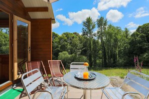 Une terrasse extérieure avec des chaises et une table en métal, un verre de jus de fruits et une bouteille.