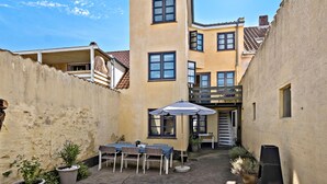 A courtyard with a table and chairs, a small umbrella, and potted plants. - 3 bedroom lovely home in Faaborg (Faaborg)