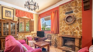 Una sala de estar acogedora con chimenea de piedra, televisión y vistas al exterior.
