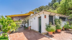 Un edificio blanco con un patio empedrado, plantas en macetas y un letrero pequeño.