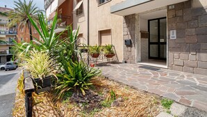 Ein Gebäude mit einer Steinaußenwand, einem Balkon mit Topfpflanzen und einer Tür mit einer Nummer.