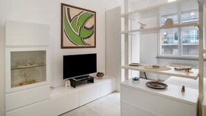 Ein modernes Wohnzimmer mit Flachbildfernseher, einer Vitrine aus Glas und einem großen abstrakten Gemälde.