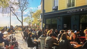 A bustling outdoor cafe with tables and chairs, a stage for live music, and a view of the sea. - COSY Belleville briapartment (Paris)
