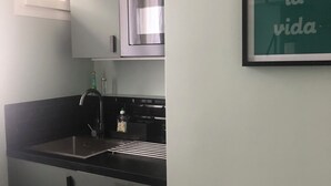 A small kitchen with a sink, a microwave, and a framed sign on the wall. - COSY Belleville briapartment (Paris)