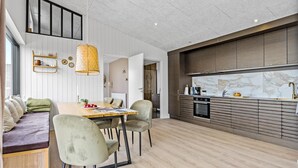Een moderne keuken met een ingebouwde oven, een groot raam en een eethoek met een houten tafel en stoelen.