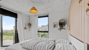 Een slaapkamer met een bed, een hanglamp, een raam en een wandplank.