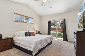 A bedroom with a bed, a nightstand, a dresser, a ceiling fan, a window, and a sliding glass door. - Woodland Haven | On Golf Resort | 10 min Bearizona (Williams)