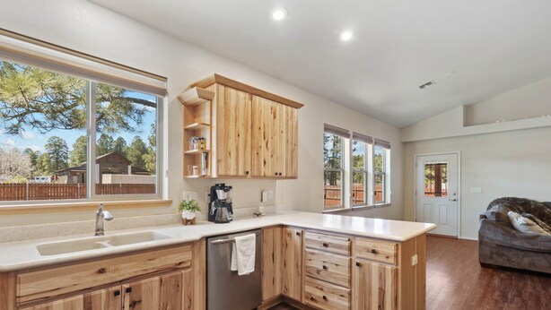 Una cocina moderna con armarios de madera, lavavajillas y un amplio ventanal.