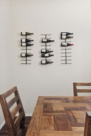 Wine is displayed on wooden racks above a dining table with chairs.
