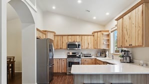Una cocina moderna con armarios de madera, electrodomésticos de acero inoxidable y una isla grande con taburetes.