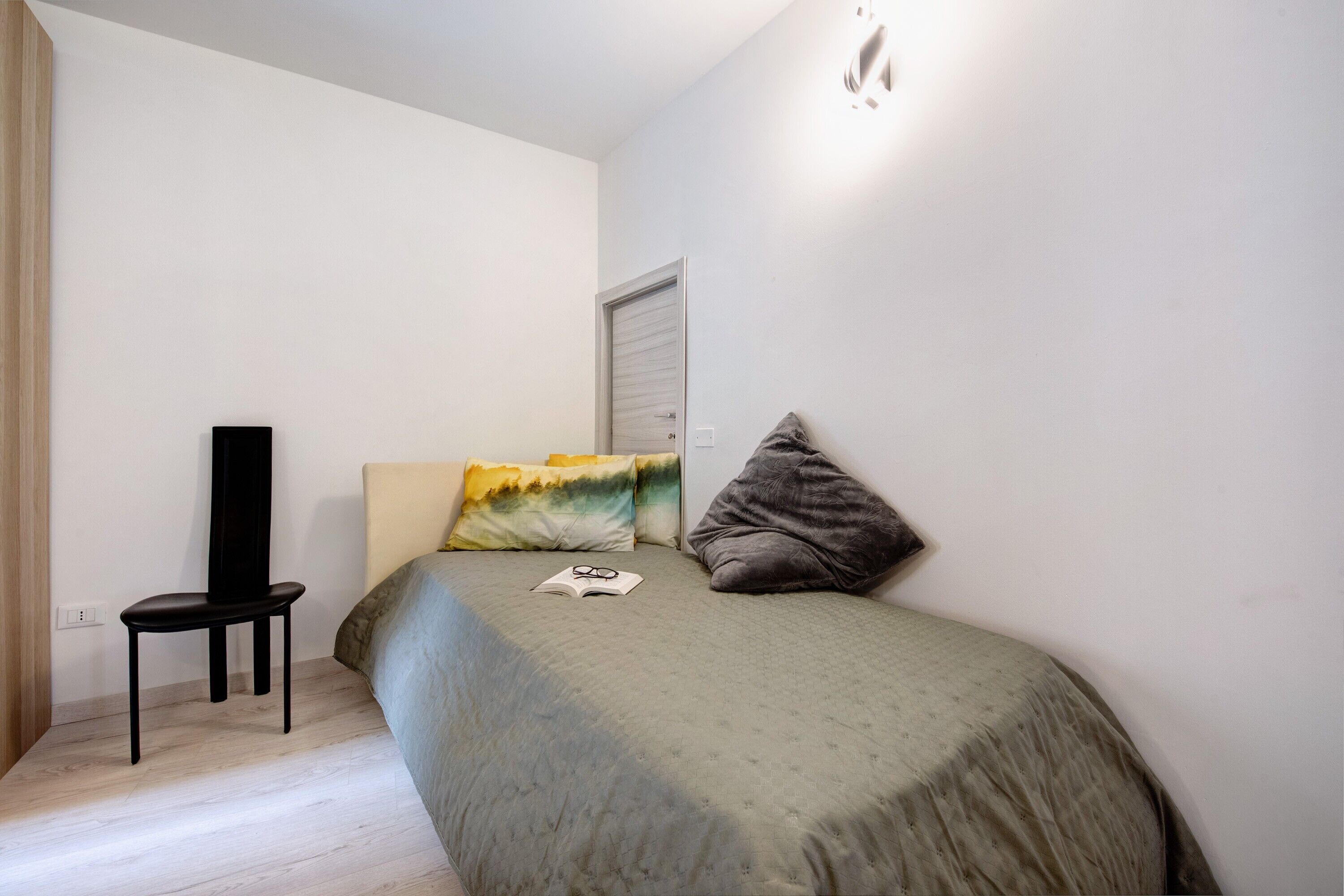 Una camera da letto con un letto, una sedia, una finestra e una porta.