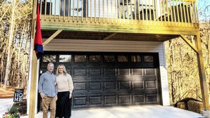 Een twee verdiepingen tellend huis met een balkon, een garage en een vlag.