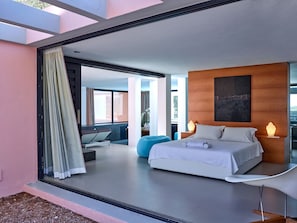 A modern hotel room with a large bed, bedside lamps, a wooden accent wall, and a view through a glass door.
