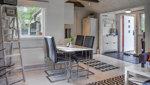 A modern kitchen with a dining area, featuring a white table, black chairs, and a ladder. - Beautiful home in åhus with WiFi (Åhus)