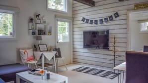 A cozy room with a wooden wall, a TV mounted on the wall, a bookshelf, and a sign that reads "Friends Welcome". - Beautiful home in åhus with WiFi (Åhus)