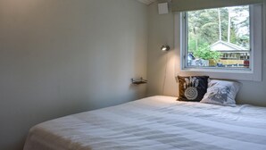 A bedroom with a bed, a window with a view of a house and trees, and a small shelf. - Beautiful home in åhus with WiFi (Åhus)