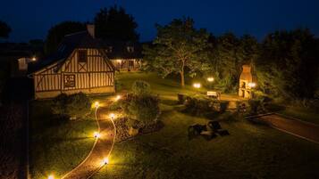 A traditional half-timbered house with a well-lit pathway leading to a seating area.