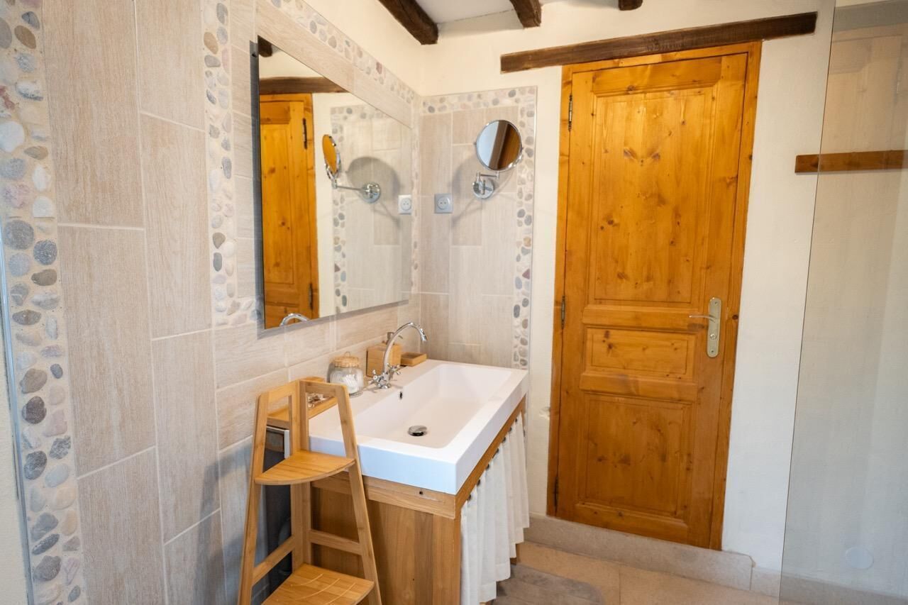 Une salle de bain avec un grand miroir, une porte en bois et un lavabo.