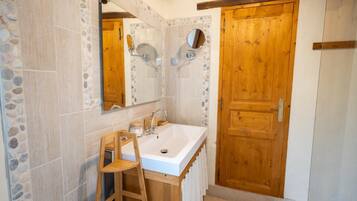Une salle de bain avec un grand miroir, une porte en bois et un lavabo.