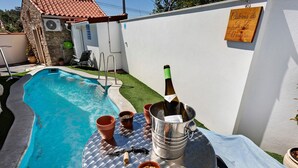 A backyard with a swimming pool, a table with a bottle of champagne, and a sign on the wall. - Apartment 'Casinha Do Rei' with Shared Terrace, Wi-Fi and Air Conditioning (Fátima)