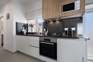 A modern kitchen with white cabinets, a black oven, a microwave, and a coffee maker. - Apartment 'Casinha Do Rei' with Shared Terrace, Wi-Fi and Air Conditioning (Fátima)