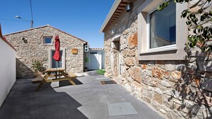 A narrow stone pathway leading to a building with a window and a red umbrella. - Apartment 'Casinha Do Rei' with Shared Terrace, Wi-Fi and Air Conditioning (Fátima)