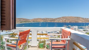 A balcony with two chairs, a table, and potted plants. - Apartment 'Agnadi' with Sea View, Balcony and Air Conditioning (Serifos)
