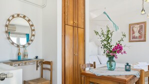 Ein Zimmer mit einem Holfischschrank, einem runden Spiegel mit Blumenrahmen, einem Esstisch mit Stühlen und einer Vase mit Blumen.