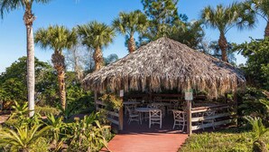 A thatched-roof pavilion with outdoor seating, surrounded by palm trees and tropical plants. - Charming Villa at Bahama Bay (Davenport)