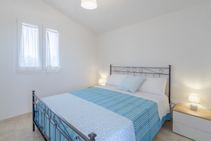 A bedroom with a bed, bedside tables, a window with curtains, and a ceiling light. - Apartment 'Appartamento Nautilus' with Sea View, Wi-Fi and Air Conditioning (Marzamemi)