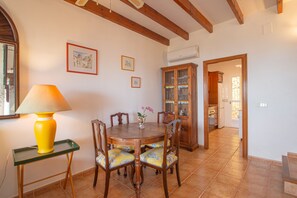 A dining area with a wooden table, chairs, a lamp, and a cabinet. - Holiday Home 'Chalet Altea' with Sea View, Wi-Fi and Air Conditioning (Altea)