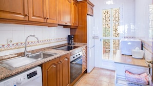 A kitchen with wooden cabinets, a stainless steel sink, a built-in oven, and a dishwasher. - Holiday Home 'Chalet Altea' with Sea View, Wi-Fi and Air Conditioning (Altea)