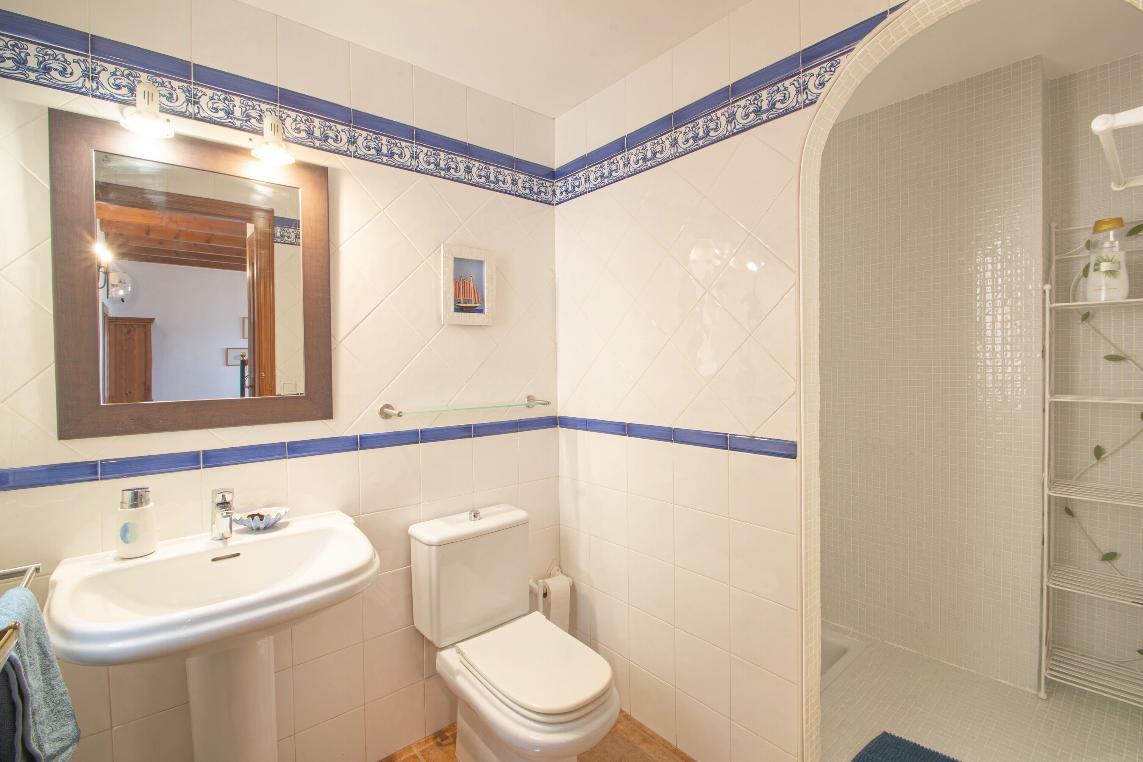 A bathroom with a sink, toilet, mirror, and shower.