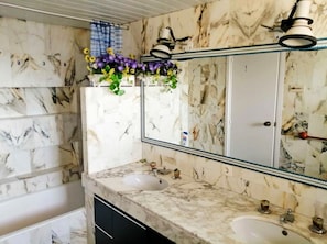 A bathroom with marble walls, two sinks, a large mirror, and a shower curtain.