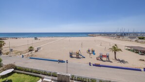 Una playa con un parque infantil, palmeras y cielo despejado.