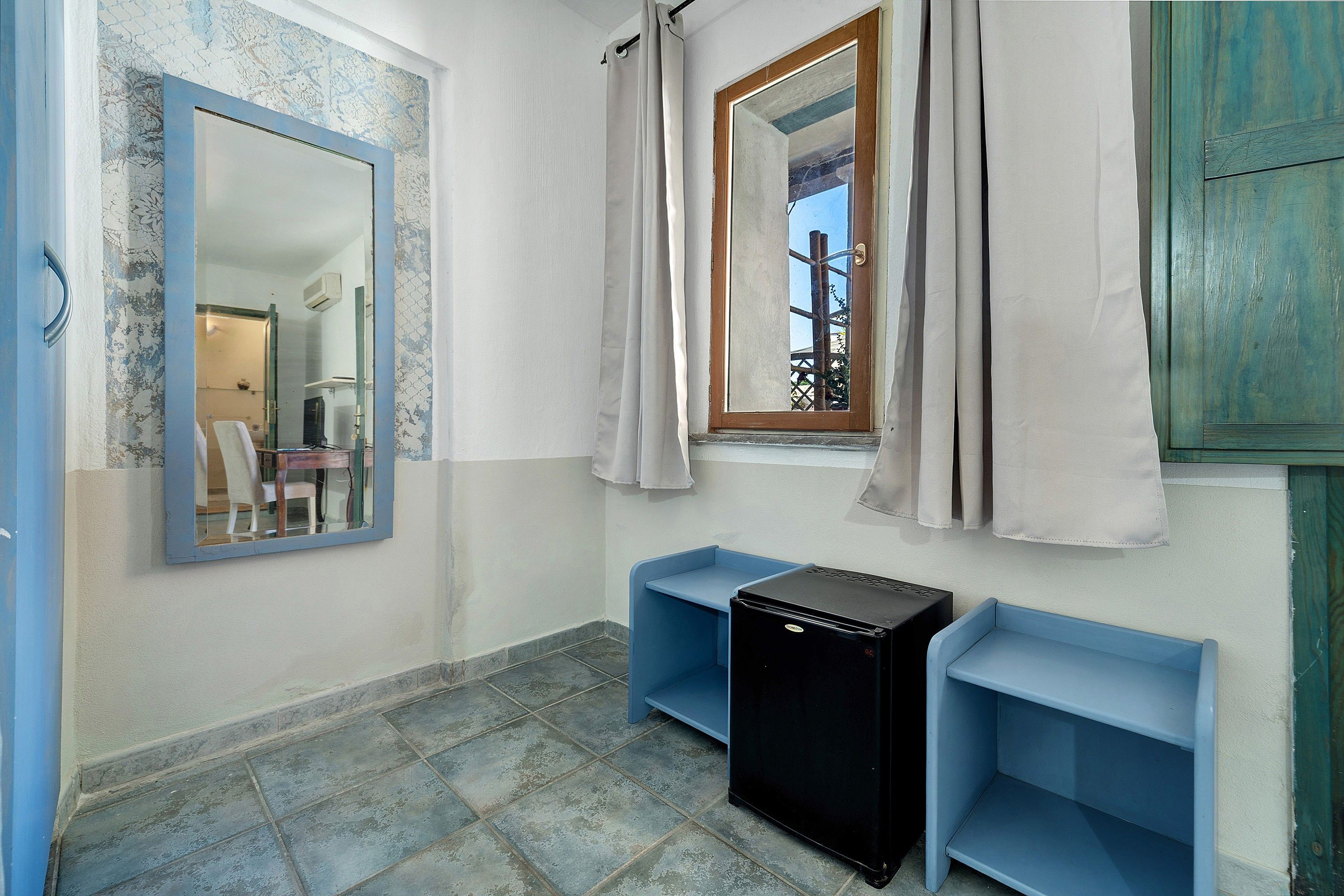 Ein Badezimmer mit Spiegel, einem fensterbelaubten Fenster, einem Waschbecken und einem schwarzen Gerät.