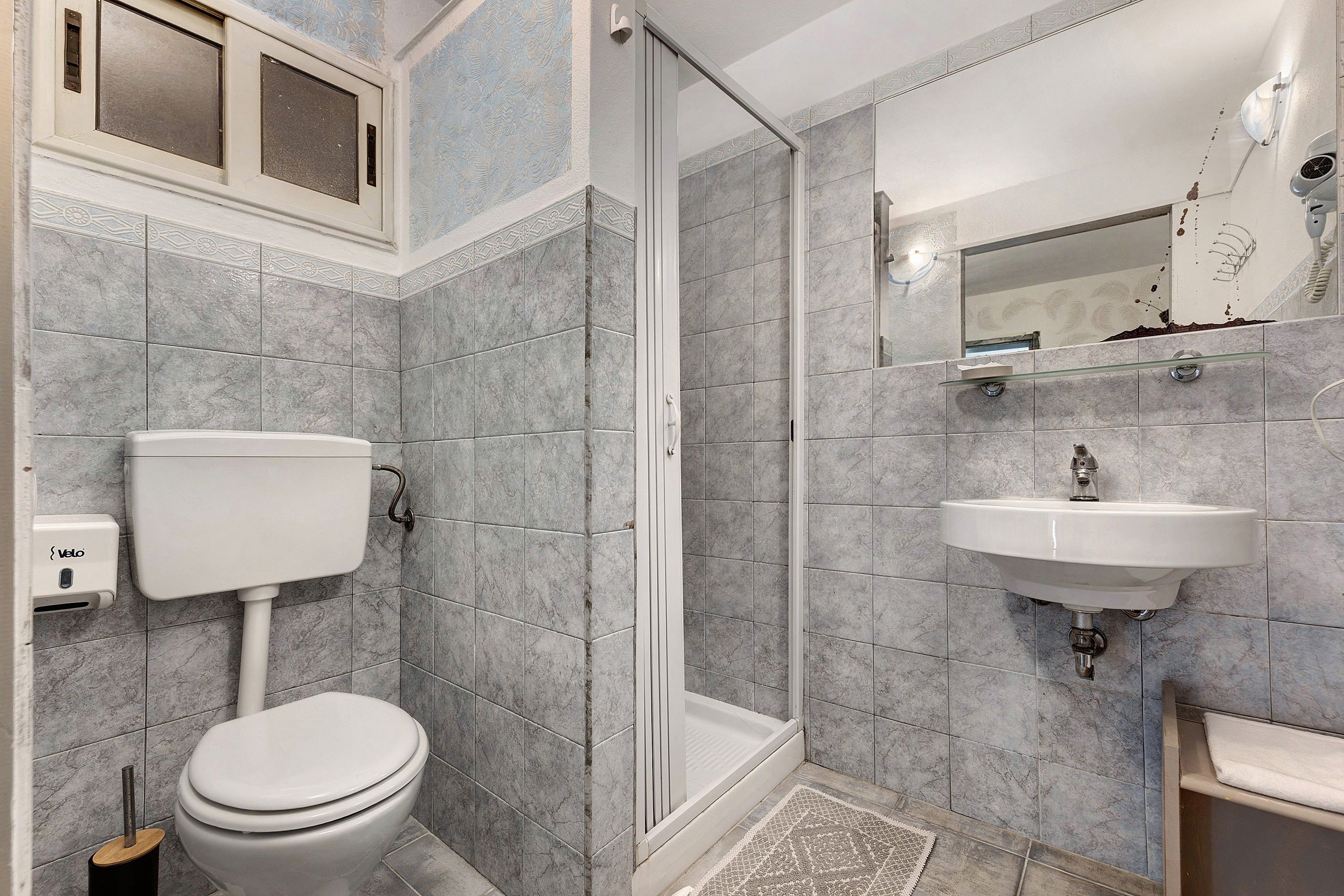 Een badkamer met toilet, douche en wastafel.