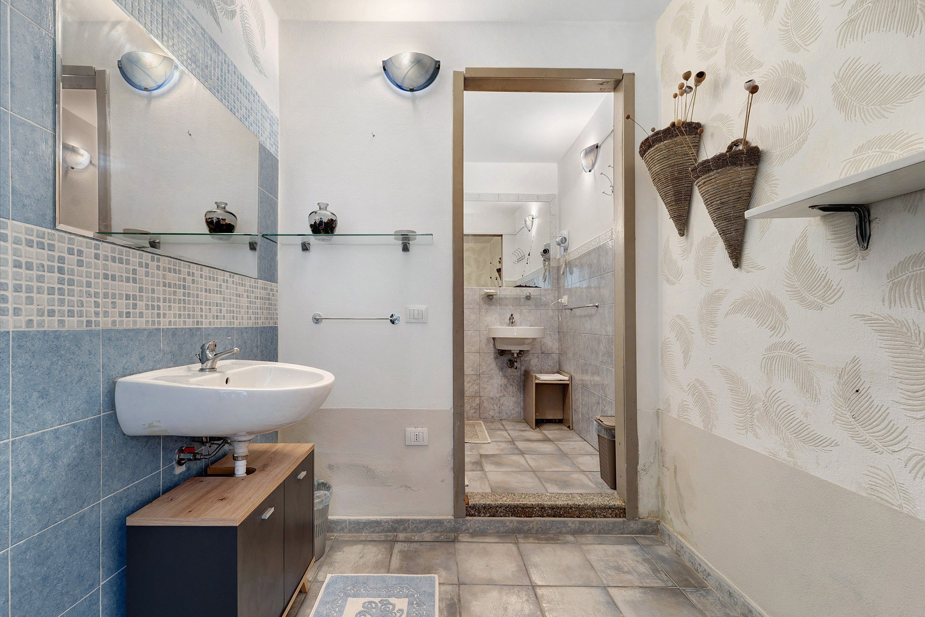 Un baño moderno con un lavamanos grande, un espejo y estantes de vidrio.