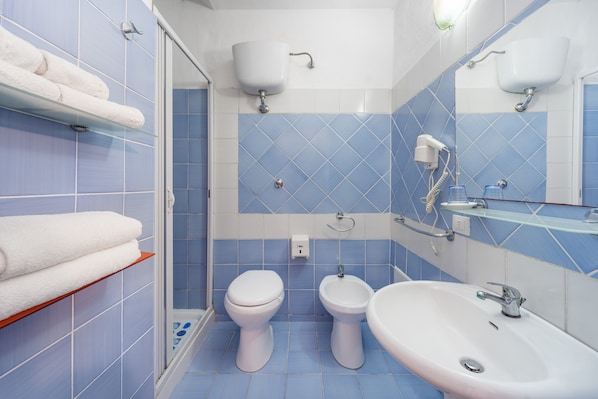 A bathroom with two toilets, a bidet, a sink, and a towel rack. - Room 'Camera 22 Doppia' with Shared Pool, Wi-Fi and Air Conditioning (Gonnesa)